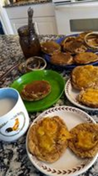 Biscuits  with jam on them on plates. A coffee cup.